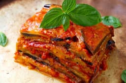 Parmigiana di melanzane e zucchine, besciamella allo yogurt e pesto di basilico
